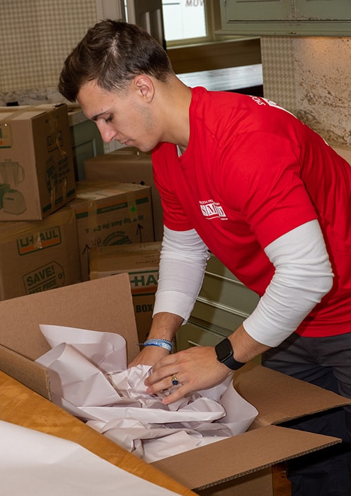 a young man wearing SMD moving red t-shirt is removing junk and putting it in the box